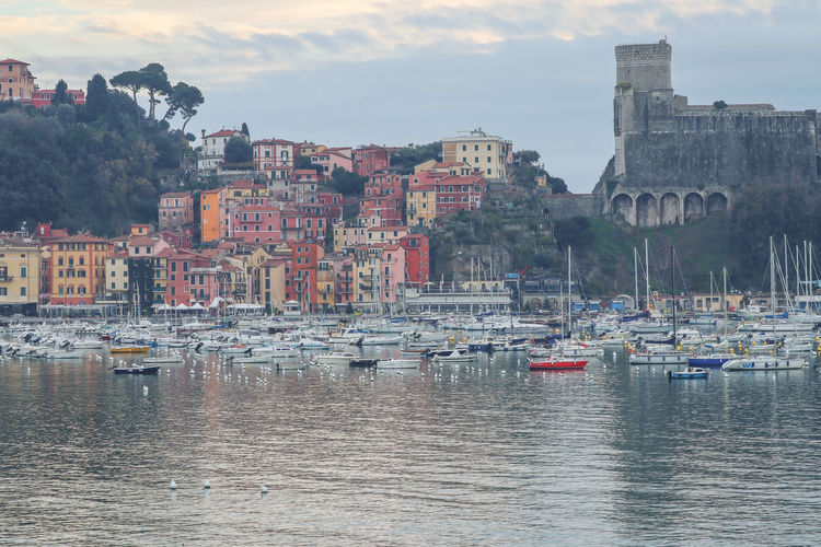 Sailboats in city by sea against sky