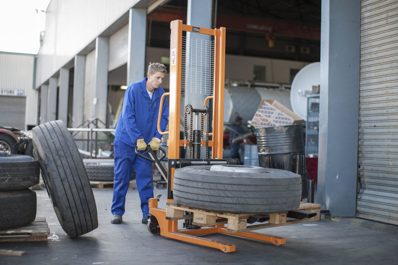 Worker moving a tire using a mobile forklift
