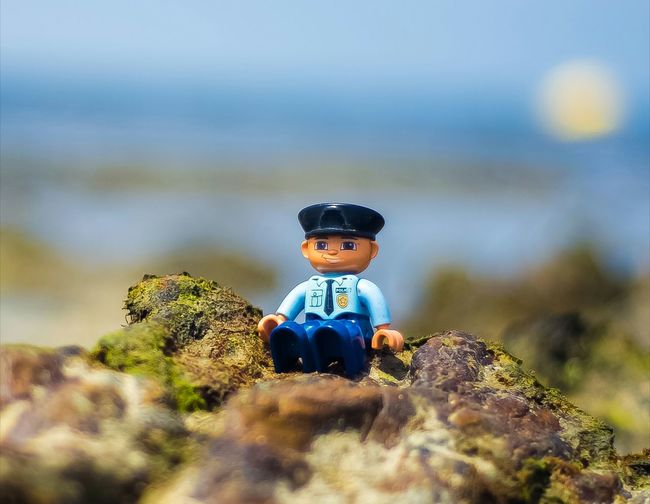 Close-up of figurine police sitting on rock 