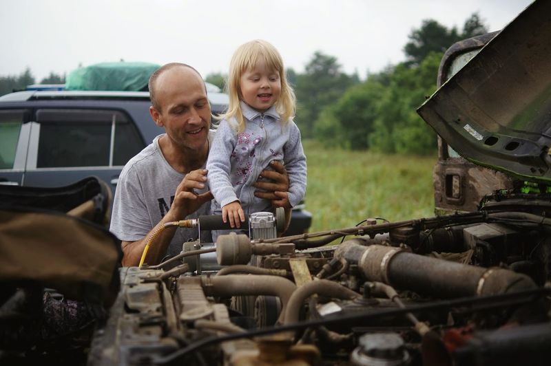 Father and daughter on field against sky