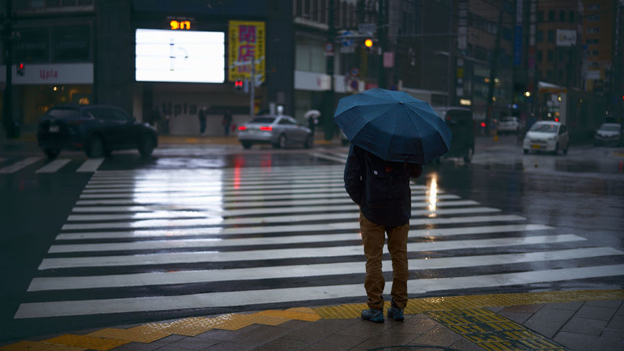Full length of man crossing road in rain