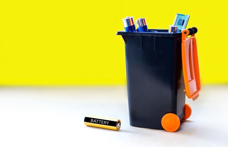 Close-up of garbage bin against yellow background
