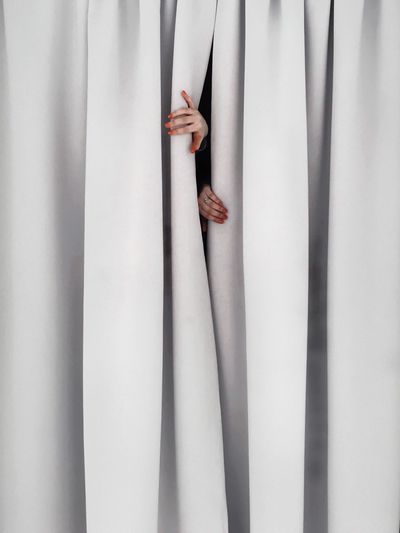 Cropped hands of woman separating curtains