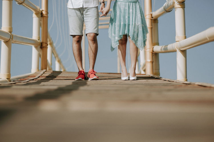 Low section of couple standing on footbridge