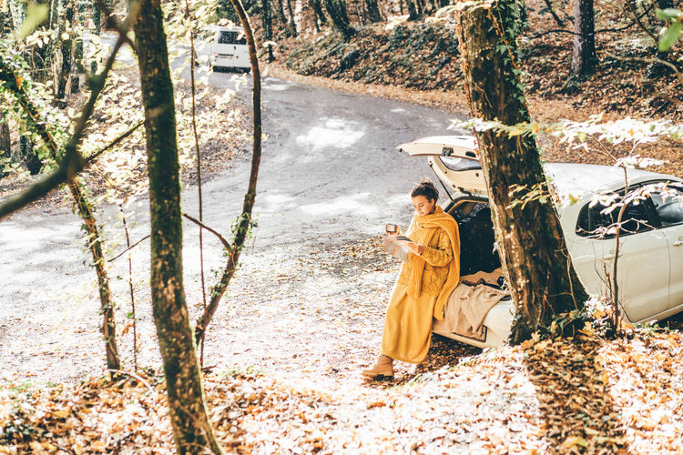 Full length of woman holding map standing by car