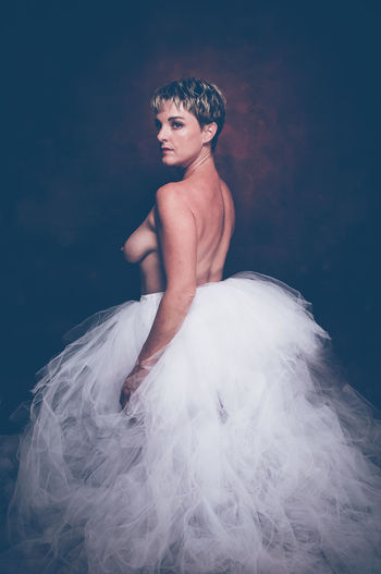 Semi-naked woman wearing tulle tutu against black background