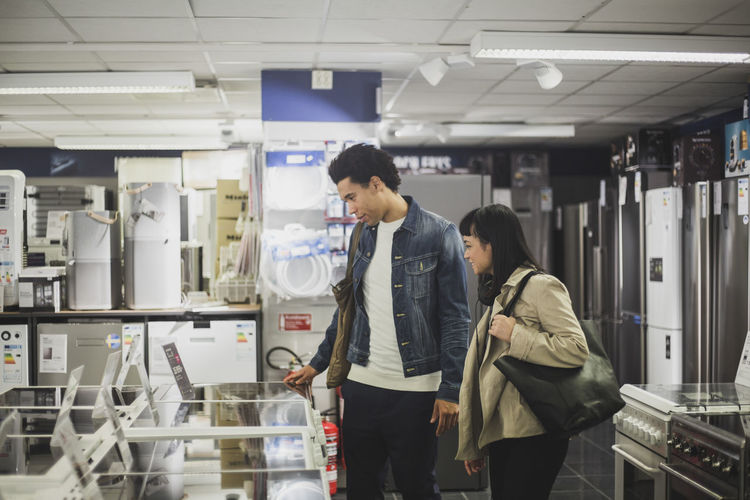 Male and female friends looking at appliances in electronics store