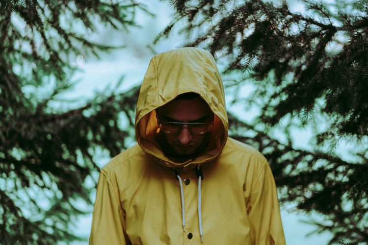 Young man wearing eyeglasses by pine tree