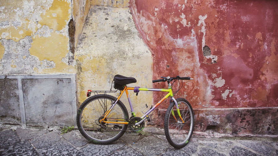 Bicycle parked against wall outdoors