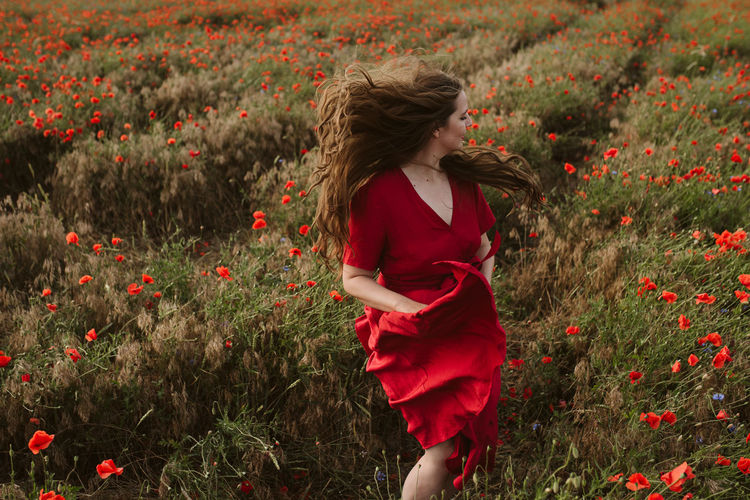 Rear view of woman with red flowers on field