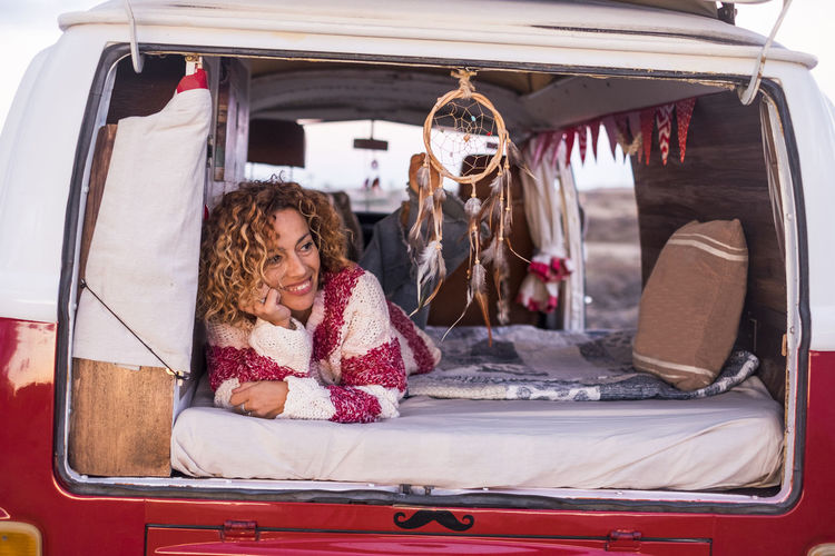 Smiling mature woman looking away while lying on bed in motor home