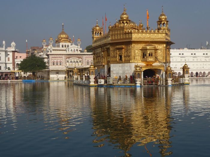 Reflection of golden temple in lake against sky