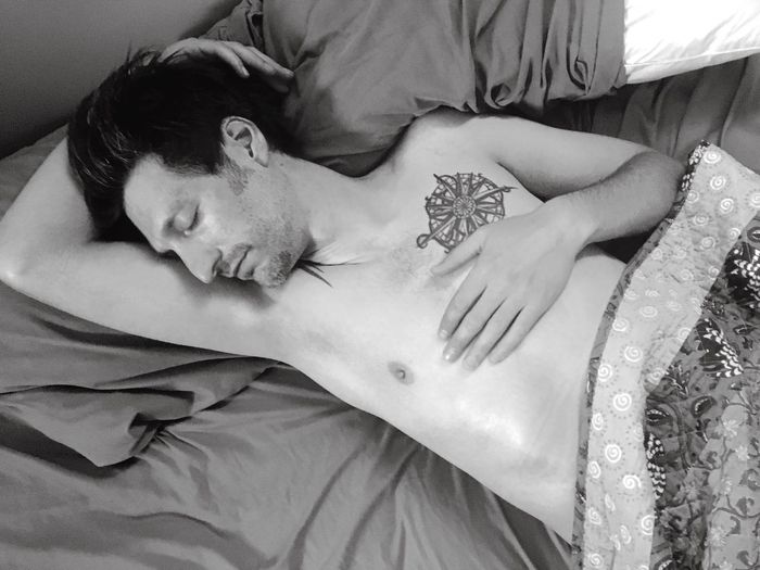 High angle view of tattooed man sleeping on bed at home