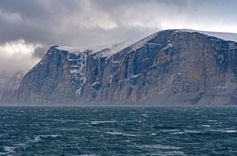 Dramatic cliffs above storm tossed seas in the sam ford fjord on baffin island in nunavut, canada
