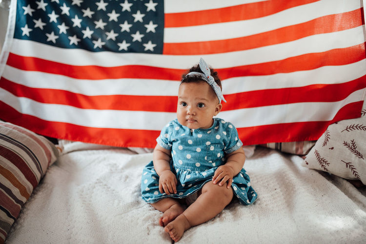 Cute girl sitting against american flag