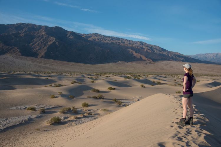 Full length of woman standing on sand in desert against sky