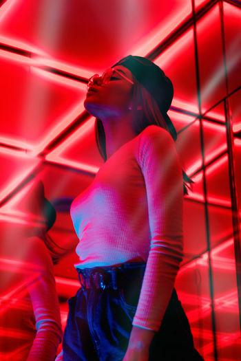 Low angle view of woman standing in illuminated red light