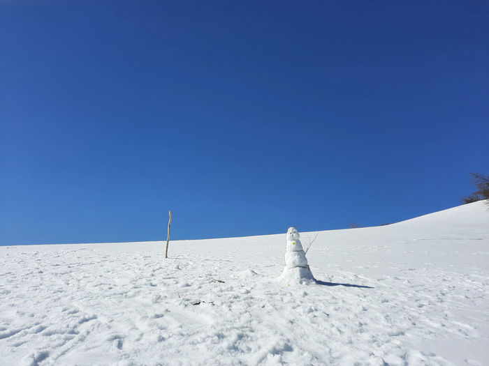 Sunny and cheerful image of a snowman in the mountains on a clear day