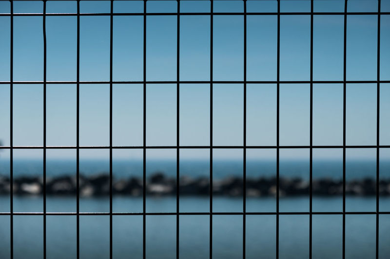 Full frame shot of metal fence against blue sky