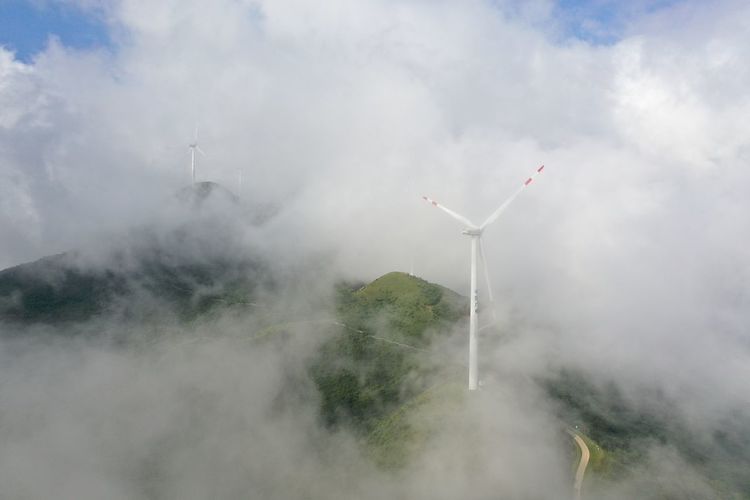Wind turbines on mountain during foggy weather
