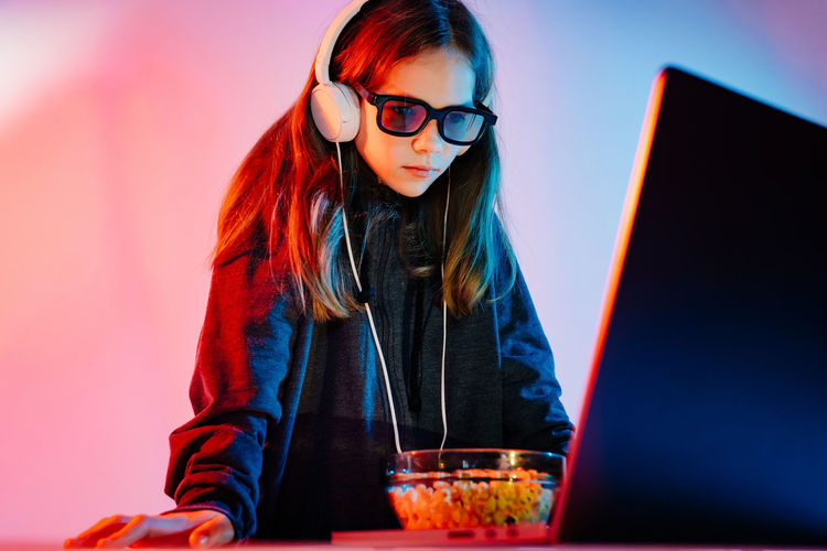 Girl wearing headphones while looking at laptop
