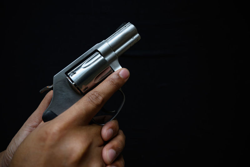 Close-up of hand holding camera over black background