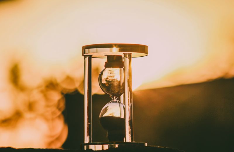 Close-up of hourglass against sky during sunset