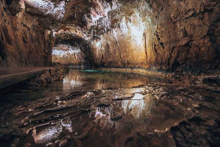 Interior of illuminated cave with water