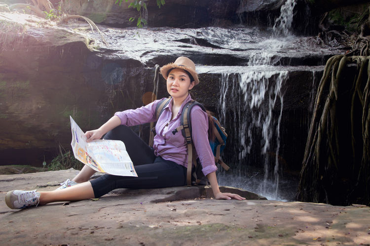 Portrait of woman sitting against waterfall