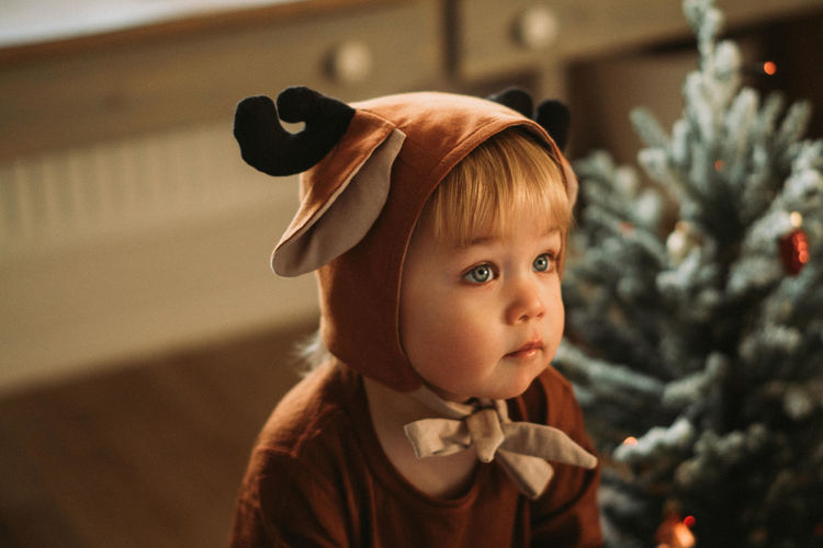 Toddler baby boy in rudolph reindeer costumes decorating christmas tree christmas tree