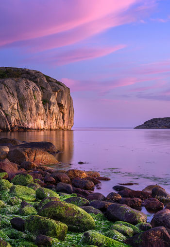 Rock formation on sea against sky during sunset