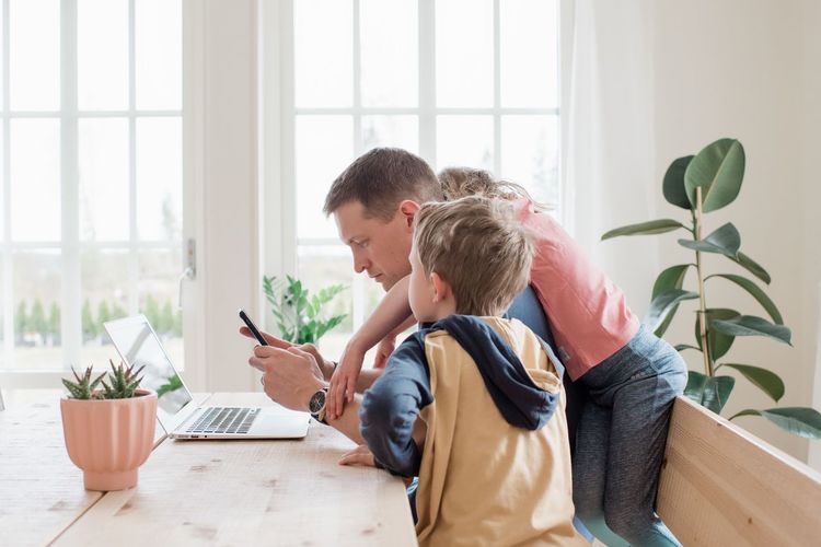 Father working from home with his kids climbing over him