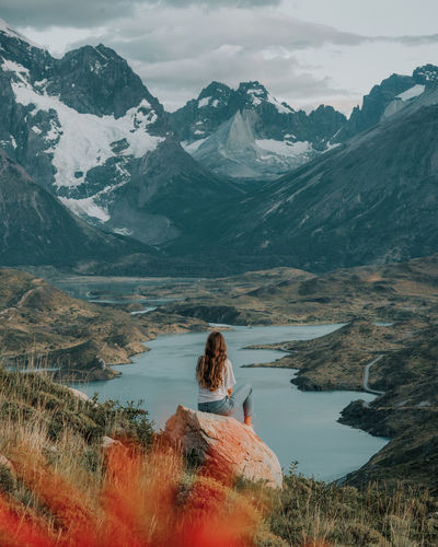 Woman sitting on rock against the mountain