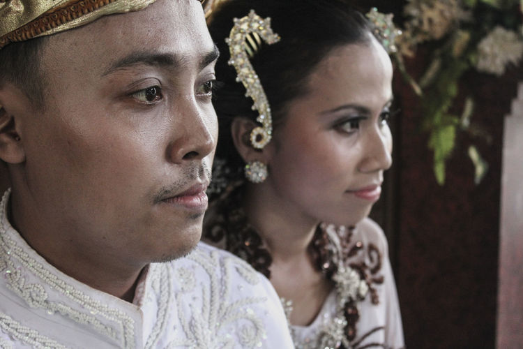 Close-up of groom and bride looking away