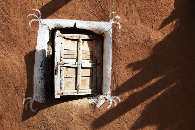 Closed wooden window of old mud hut