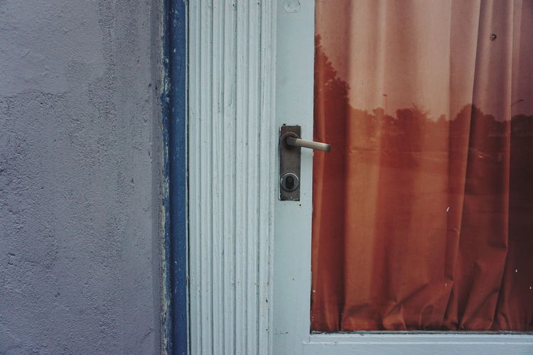 Close up of outdoor door, handle, pane of glass covered with red fabric