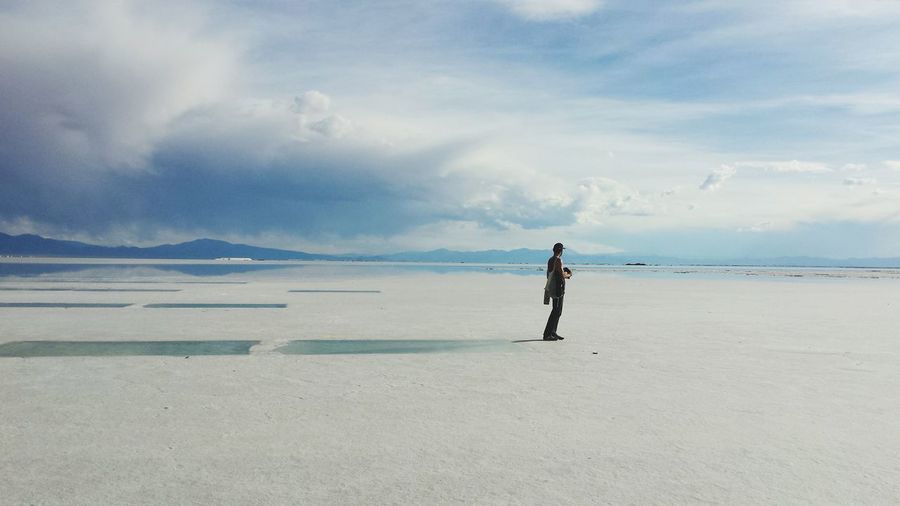 Full length of man standing at salinas grandes against cloudy sky