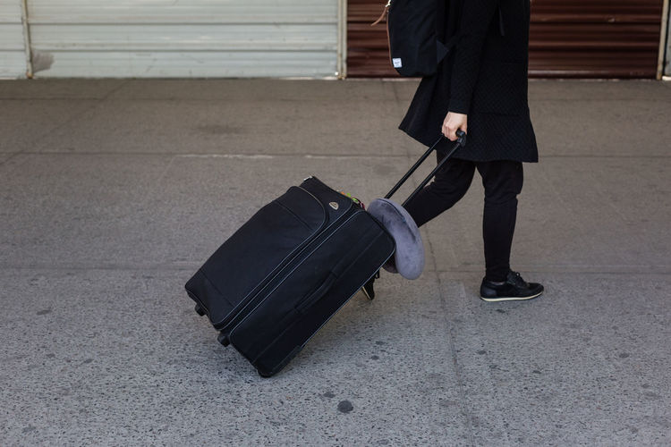 Low section of man with luggage walking on footpath