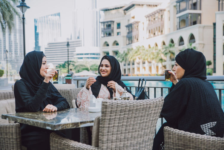 Smiling women in hijab sitting outdoors