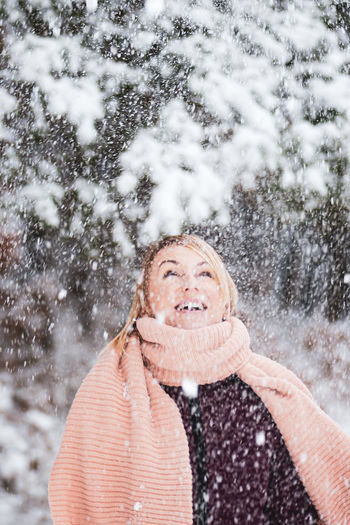 Cheerful woman playing with snow while standing outdoors