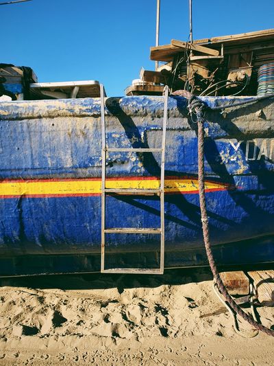 View of boats moored on beach against clear blue sky
