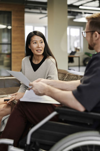 Businesswoman talking to disabled colleague in office