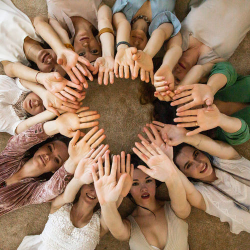 High angle view of people showing hands while lying on floor
