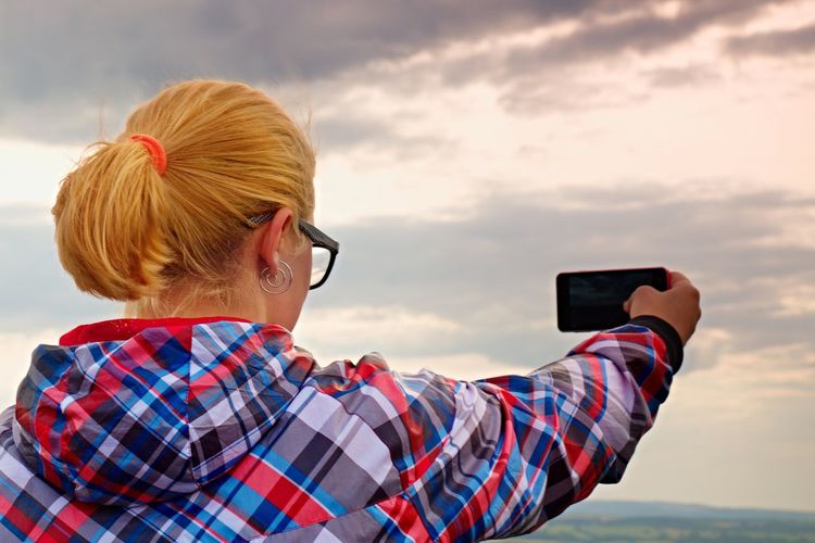 Hiking blonde woman taking photo with smart phone at mountains.