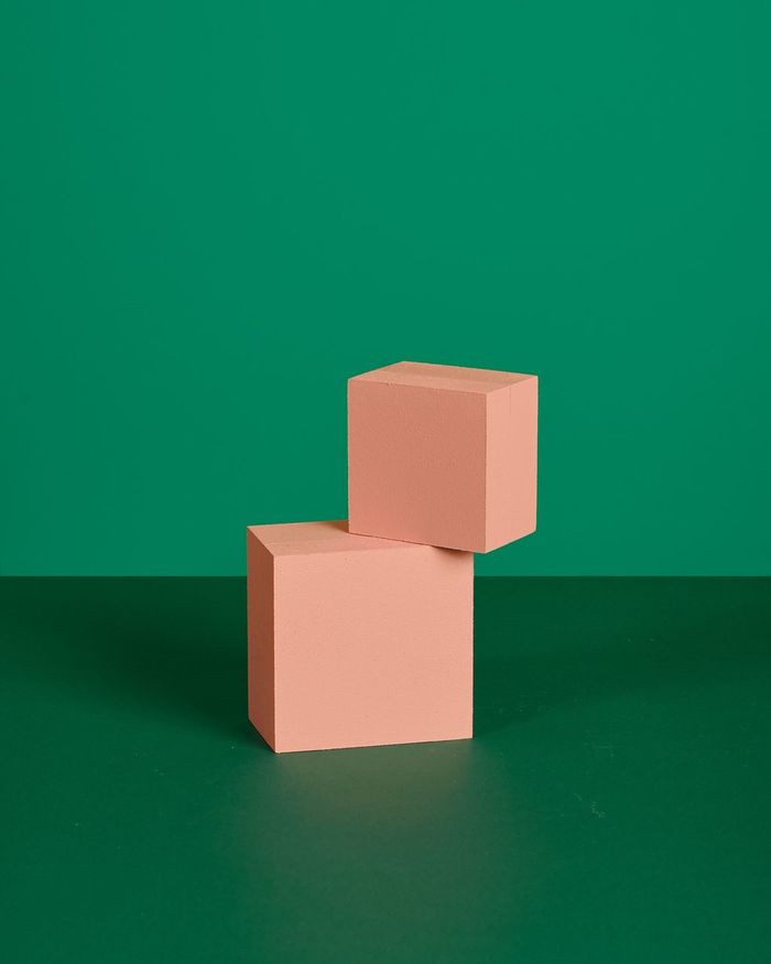 Close-up of coral colored cube shapes over green background