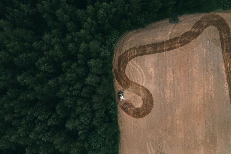 Aerial view of arable land with traces of tire harrows and tractors. patterns on the ground.