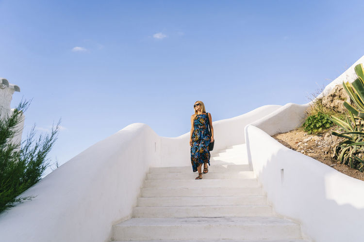 Mature woman moving down on steps against clear blue sky