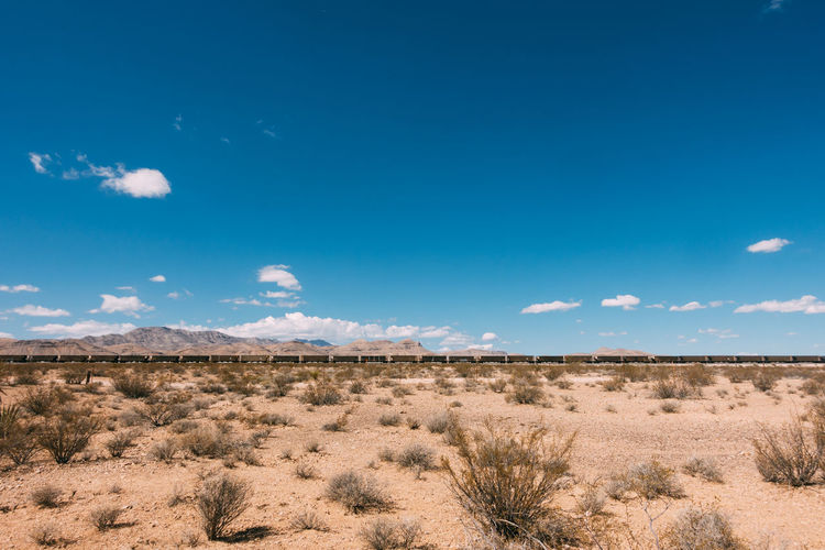 Freight train at desert against blue sky