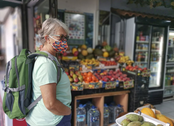 Senior woman wearing mask standing at market stall