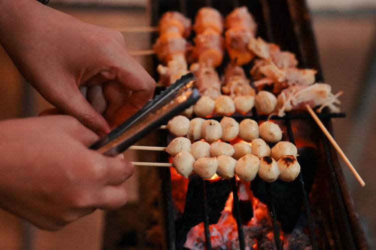 Midsection of person preparing food on barbecue grill